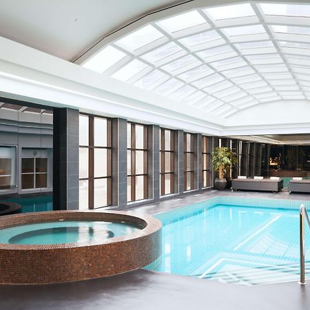 Hotel Stamford Plaza Melbourne City Exterior foto The photo shows an indoor swimming pool area. The pool is rectangular and has clear blue water, surrounded by a sleek, modern design. On one side, there is a round hot tub made of dark stone. Large windows line the walls, allowing natural light to fi