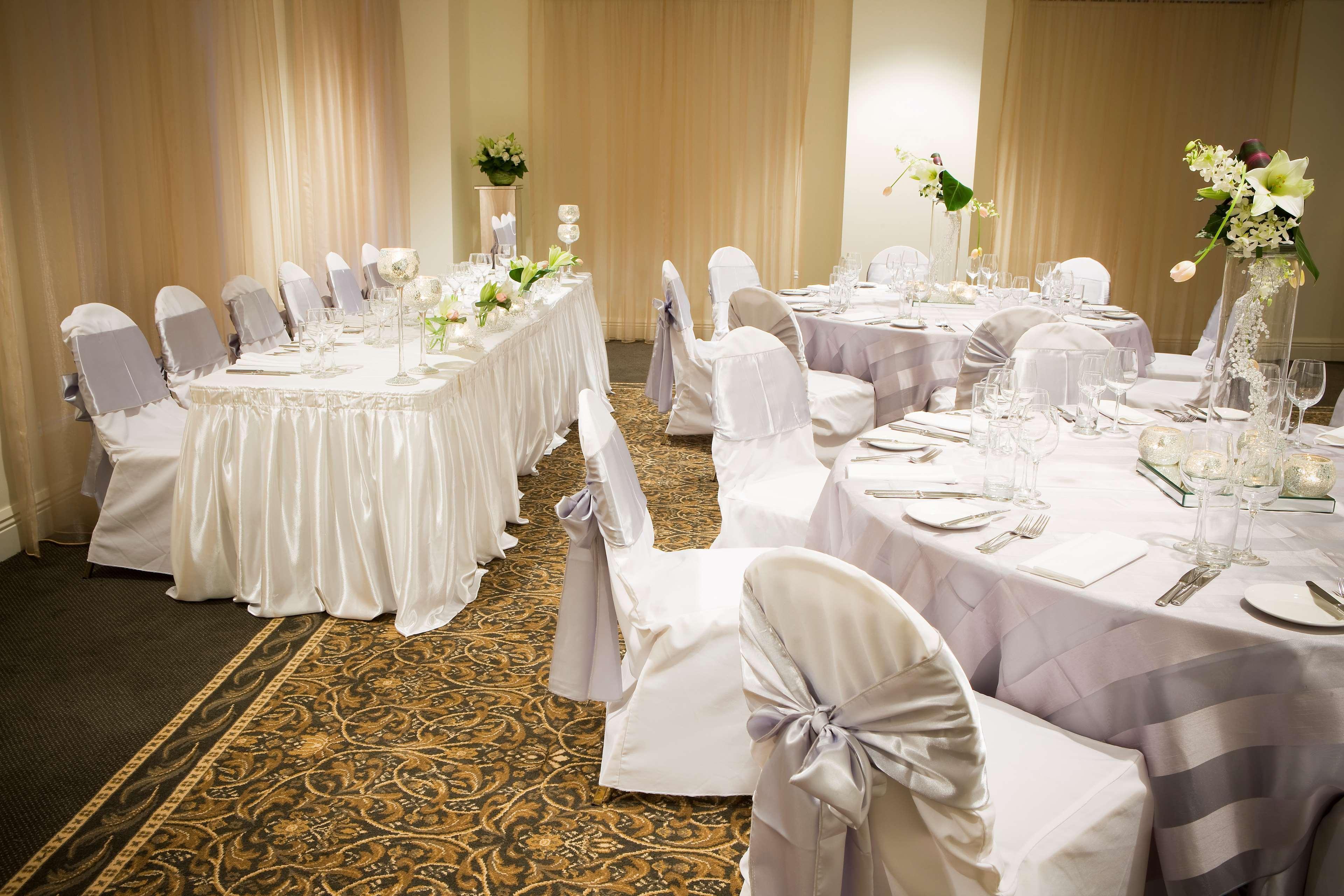 Hotel Stamford Plaza Melbourne City Exterior foto The photo depicts an elegantly set dining area, likely for a special event or celebration. There are several round tables covered with tablecloths, each set with plates, glassware, and cutlery. The chairs are dressed in white covers, some adorned wit