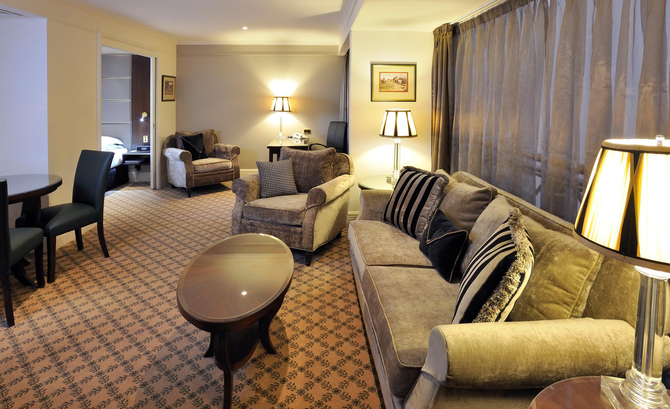 Hotel Stamford Plaza Melbourne City Exterior foto The photo shows a stylish and comfortable living area. It features plush seating, including a sofa with decorative cushions and a couple of armchairs. There's a circular coffee table in the center of the seating arrangement. The room has soft lightin