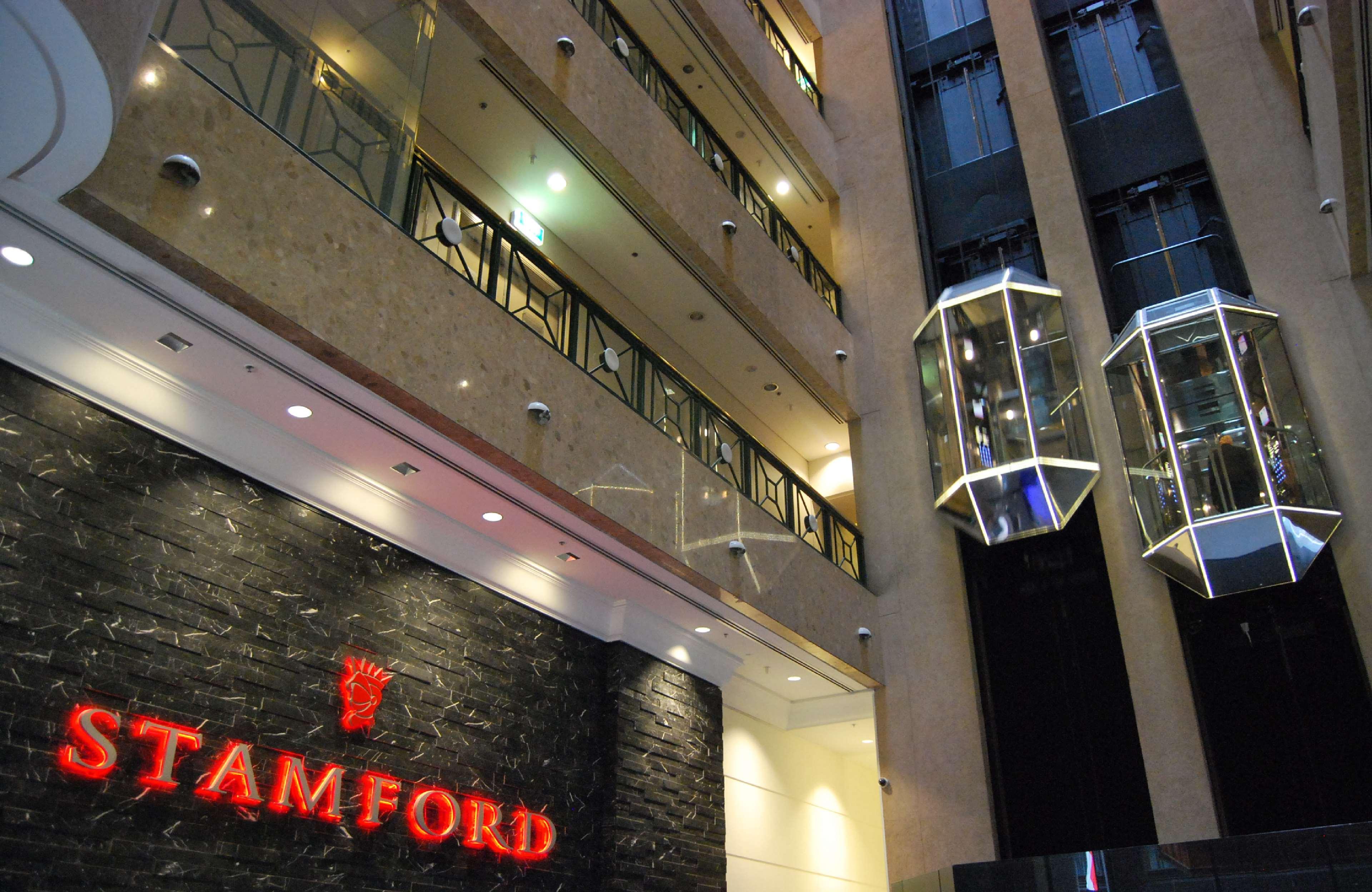 Hotel Stamford Plaza Melbourne City Exterior foto The photo shows the interior of a building, likely a hotel or commercial space. There is a prominent sign with the name "STAMFORD" in red lettering against a dark stone background. The building features several floors, visible from the photograph, wi