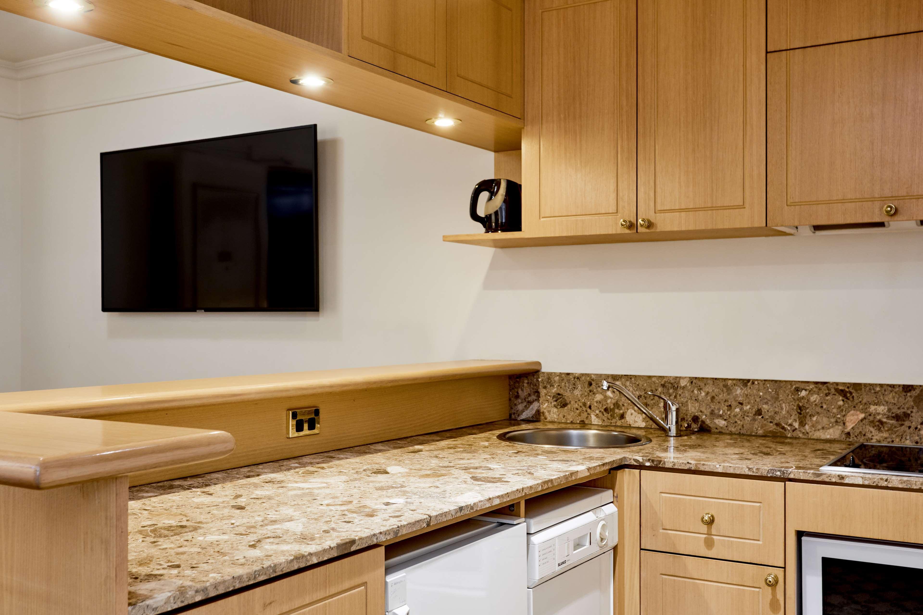 Hotel Stamford Plaza Melbourne City Exterior foto The photo shows a modern kitchen with wooden cabinetry and a granite countertop. There's a stainless steel sink integrated into the countertop, and appliances including a dishwasher and possibly a coffee maker on the shelf above. A flat-screen televi