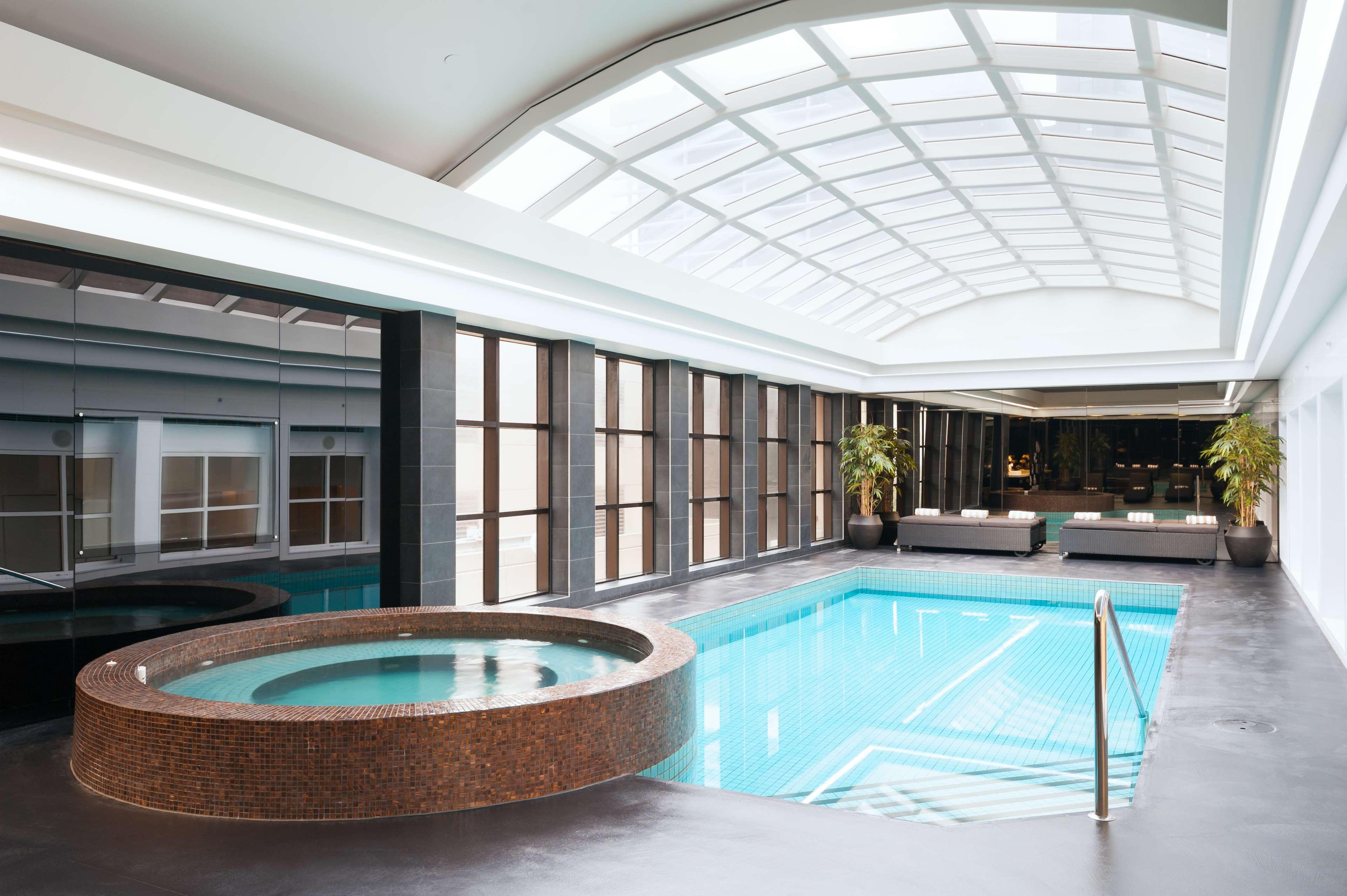 Hotel Stamford Plaza Melbourne City Exterior foto The photo shows an indoor swimming pool area. The pool is rectangular and has clear blue water, surrounded by a sleek, modern design. On one side, there is a round hot tub made of dark stone. Large windows line the walls, allowing natural light to fi