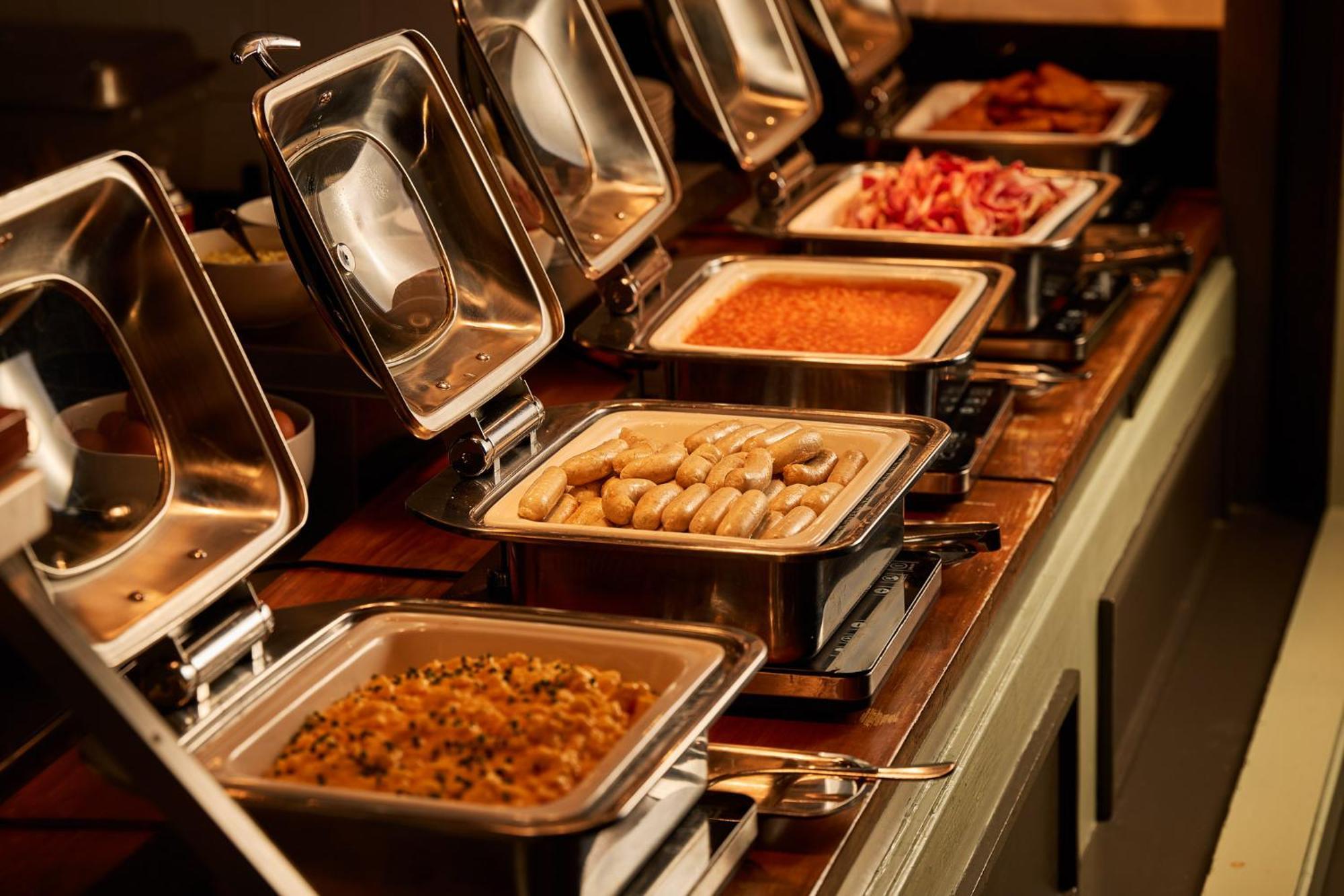 Hotel Stamford Plaza Melbourne City Exterior foto The photo depicts a buffet setup featuring multiple food trays in stainless steel chafing dishes. Each dish is opened to display different types of food. The dishes contain a variety of items, which might include a mix of proteins, vegetables, or sta