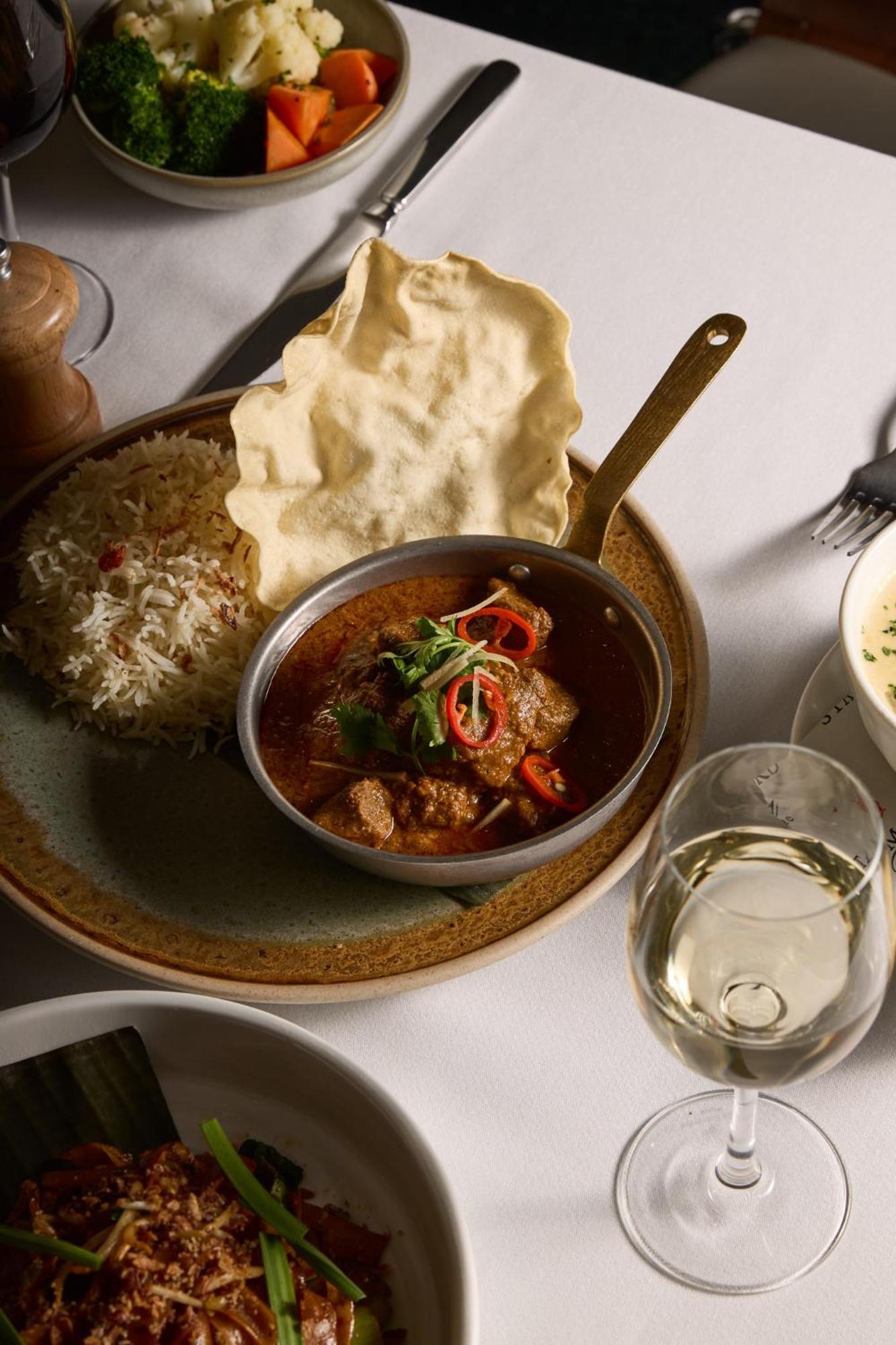 Hotel Stamford Plaza Melbourne City Exterior foto The photo features a plated meal that includes a serving of meat curry in a small round dish. The curry is garnished with herbs and slices of chili. Accompanying the curry, there is a mound of fluffy rice, and a piece of crispy flatbread (poppadom) r