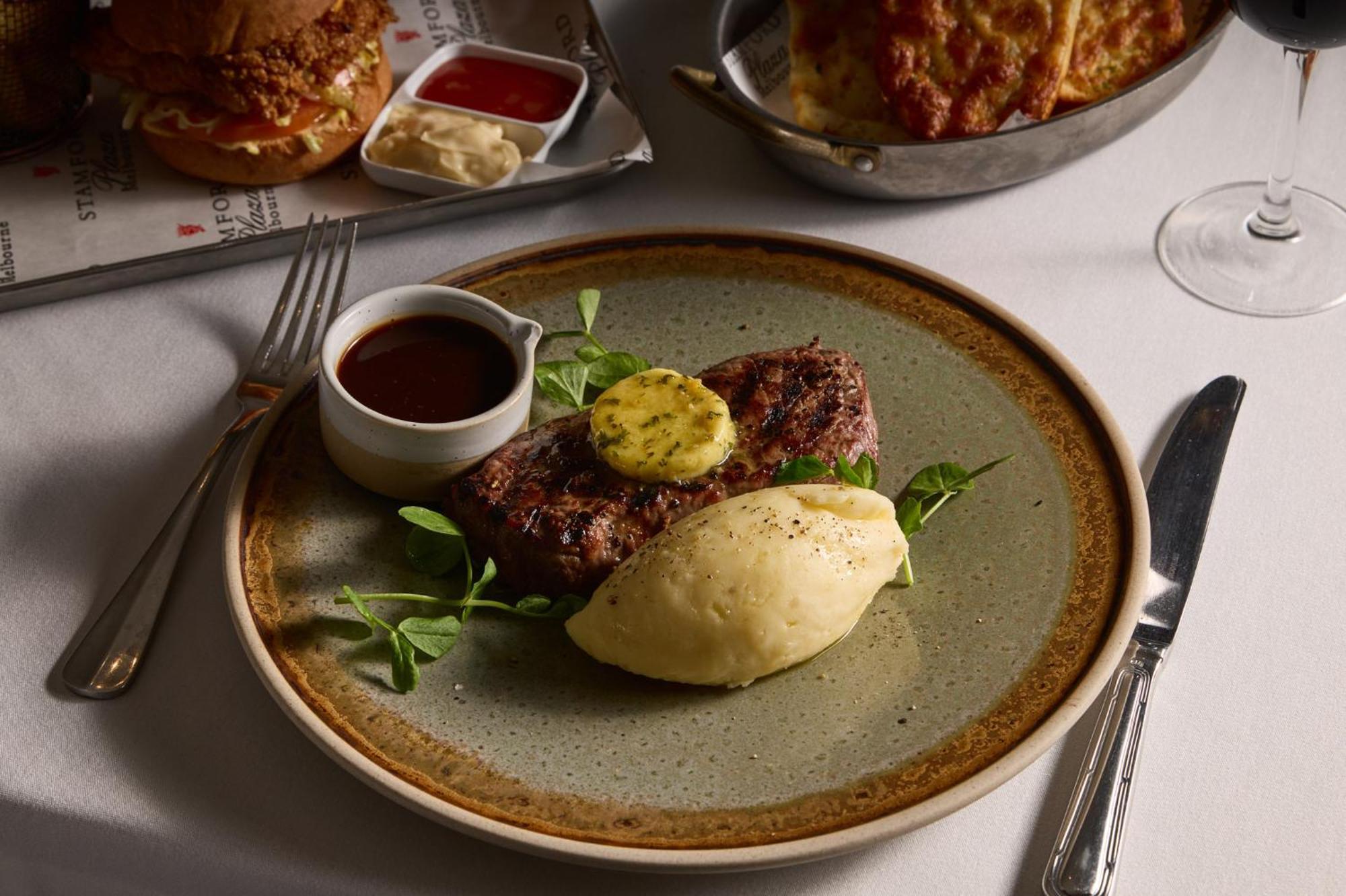 Hotel Stamford Plaza Melbourne City Exterior foto The photo shows a well-presented plate featuring a serving of steak, topped with a dollop of herb butter and surrounded by fresh sprouts or microgreens. There is a smooth portion of mashed potatoes beside the steak, and a small bowl of sauce, likely 