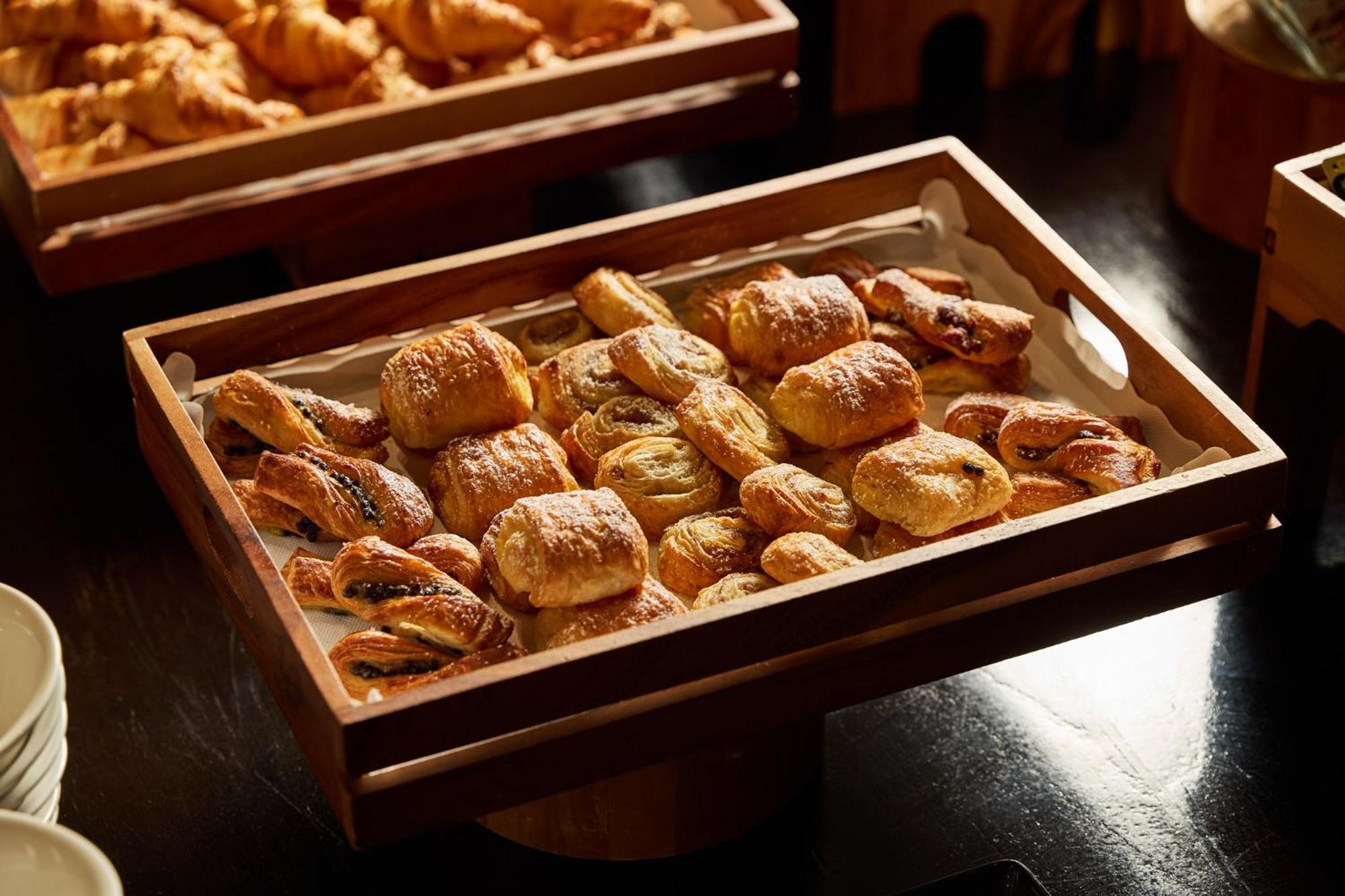 Hotel Stamford Plaza Melbourne City Exterior foto The photo shows a wooden tray filled with an assortment of baked goods. There are various types of pastries, including small, flaky items that appear to be puff pastries, and possibly some filled with chocolate or fruit. The pastries are golden brown