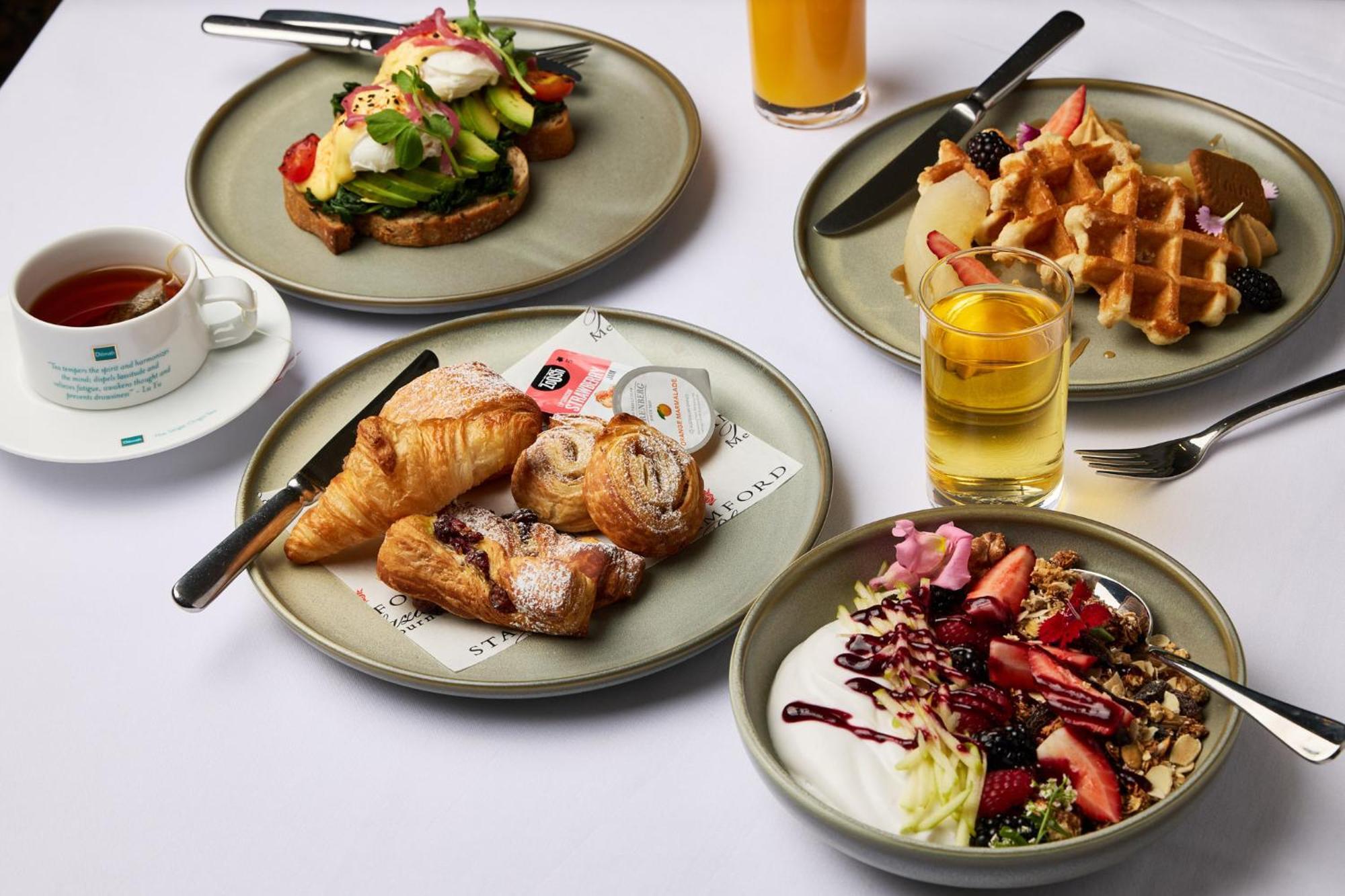 Hotel Stamford Plaza Melbourne City Exterior foto The photo displays a variety of breakfast items arranged on several plates. 

1. **Top-left Plate**: Features an open-faced sandwich with avocado, topped with poached eggs and garnished with vegetables.
2. **Top-right Plate**: Contains freshly made w